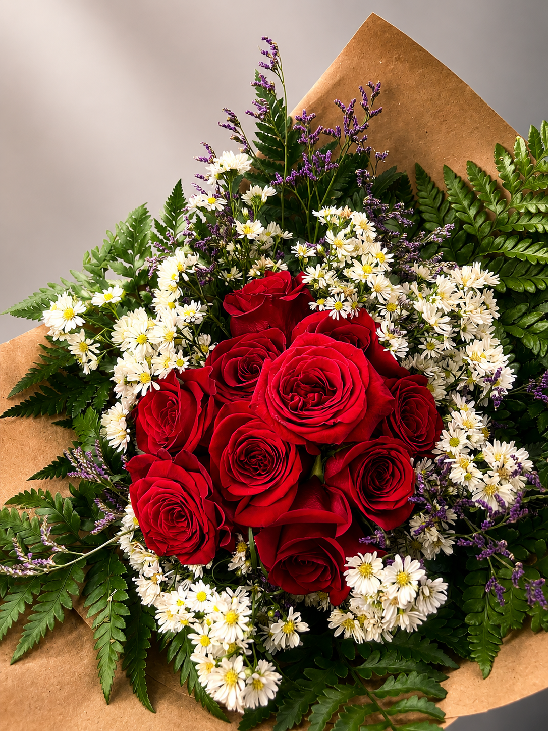 Detalhe do buquê O Eterno com rosas vermelhas e flores delicadas