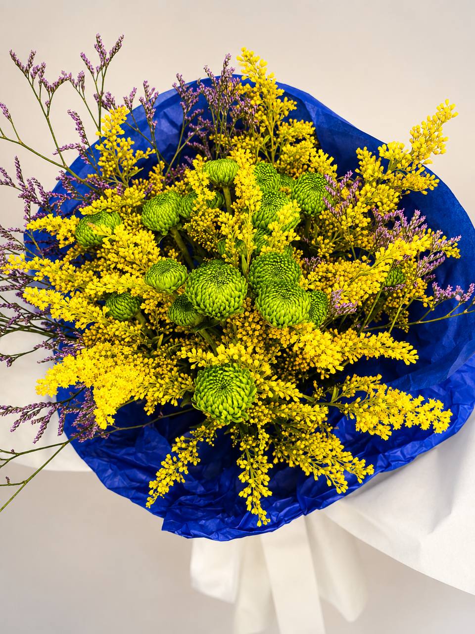 Buquê do Hexa com flores amarelas, verdes e lilás em embalagem azul e branca